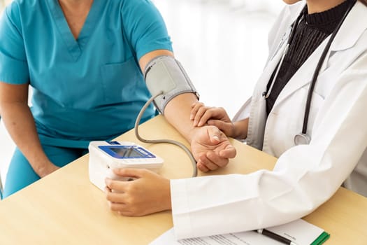 Female doctor measuring blood pressure of senior woman elderly at examination room in hospital clinic.