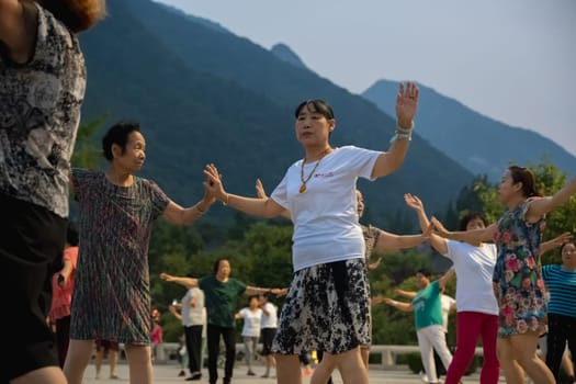 Huashan, China -  August 2019 : Group of Chinese women dancing in the open plaza square at the foot of HuaShan mountain at dusk, Shaanxi Province