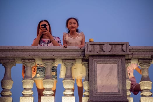 Guilin, China -  August 2019 : Mother with her children looking down from the road Bridge over the estuary of Rong and Shan Lakes at night, Guilin town, Guangxi Province