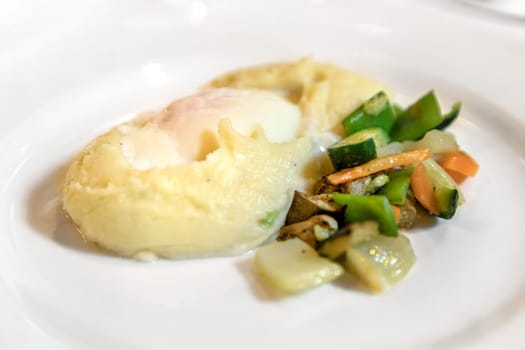 Plate of mashed potato with egg served with vegetable side dish. Prepared for wedding, event or other.