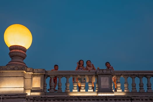 Guilin, China -  August 2019 : Mother with her children looking down from the road Bridge over the estuary of Rong and Shan Lakes at night, Guilin town, Guangxi Province