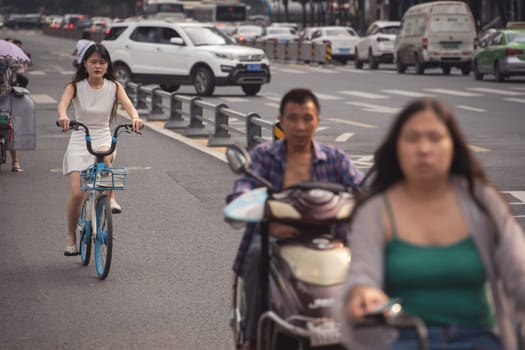 Chengdu, China -  July 2019 : Commuters riding on bicycles, scooters and motorbikes on the busy street in summer, Sichuan Province