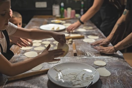 Chengdu, China -  July 2019 : Children and adults learning the art of making of traditional chinese dumplings during cooking class in a travellers hostel