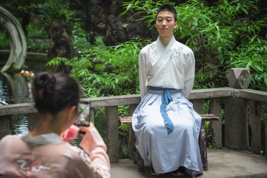 Chengdu, China -  July 2019 :  Young bride taking photo of her groom posing at a wedding ceremony in the park
