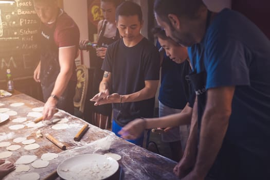 Chengdu, China -  July 2019 : People learning the art of making of traditional chinese dumplings during cooking class in a travellers hostel