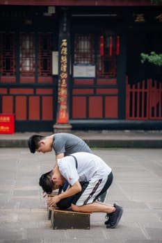 Chengdu, China - July 2019 : Chinese men praying and worshiping at the Wenshu Chinese Buddhist Temple