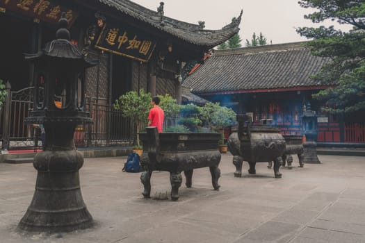 Chengdu, China - July 2019 : Chinese person praying, worshiping, burning incense sticks, giving alms and thanks at the Wenshu Chinese Buddhist Temple