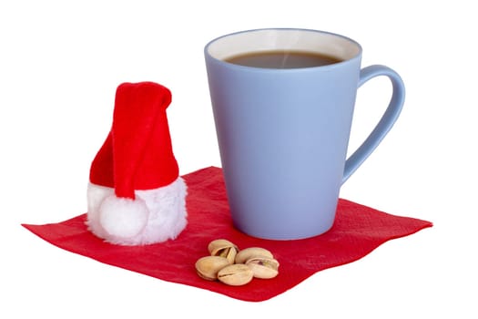 Coffee cup background isolated. Close-up of a blue coffee mug and pistachios with a Santa hat on a red napkin isolated on a white background. Concept morning coffee in christmas time. Macro.