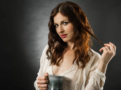 Beautiful happy redhead woman drinking coffee over dark background.