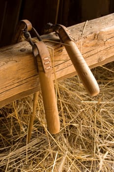Two threshing flais hanging over an arbor with some straw underneath