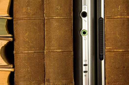 Laptop standing between antiquated books like in a library