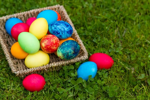 Happy Easter, colorful eggs in a basket on a grass