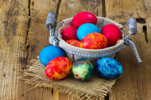 Happy Easter, colorful eggs in a basket on wooden background