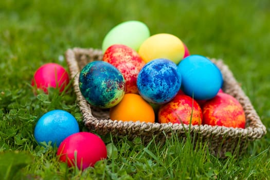 Happy Easter, colorful eggs in a basket on a grass