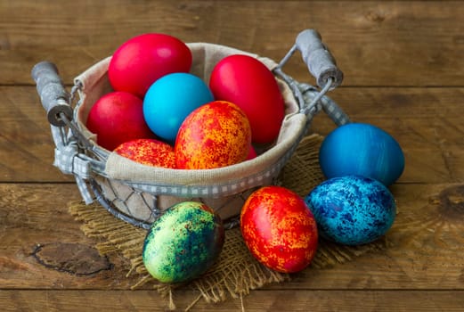 Happy Easter, colorful eggs in a basket on wooden background