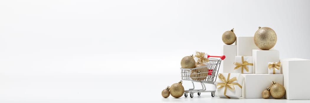 Shopping trolley, gift boxes and Christmas decorations isolated on white background with copy space. Christmas and New Year shopping. Winter sale. For design of advertising, web design