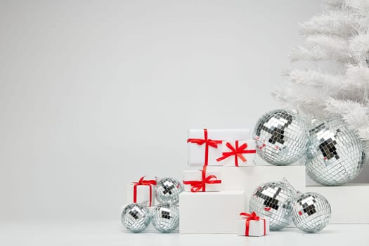 Festive composition with white geometrical figures, Christmas fir tree and mirorr balls isolated on white background with copy space. For design of advertising, web design. Christmas and New Year