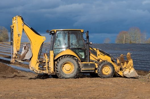 Small yellow excavator stay at the beds after work.
