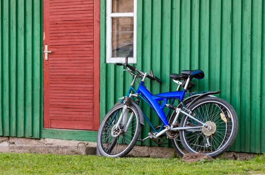 Old bicycles parked near a wood wall and doors