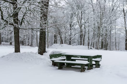 Wooden picnic table with benches after heavy snowfall