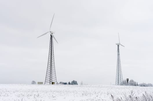 Two modern wind turbines in winter landscape.