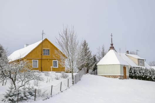Winter landscape with village houses with snow on roof.