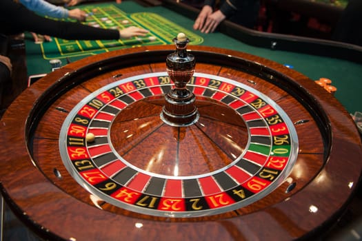 Casino, gambling and entertainment concept - roulette table and stack of poker chips