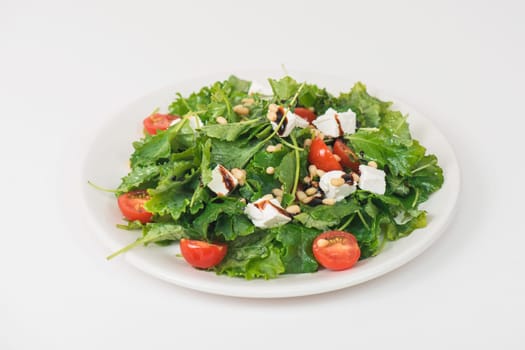 Green salad with vegetables: greens, arugula, tomato, cheese pine nuts and sauce