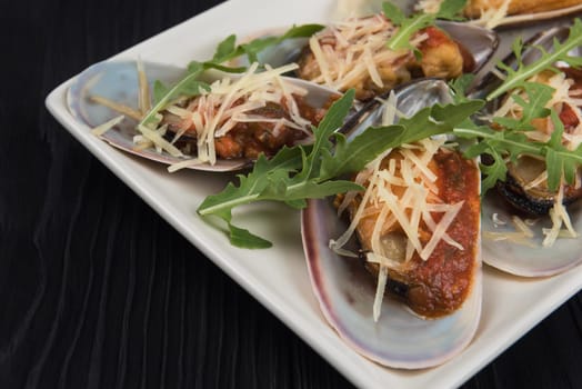 Cooked mussels with sauce cheese and arugula