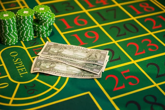 Casino, gambling and entertainment concept - roulette table and stack of poker chips