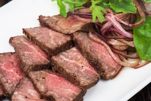 Plate with meat cutting and fresh greens on white plate