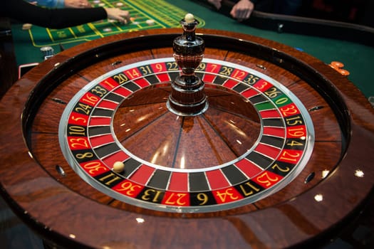 Casino, gambling and entertainment concept - roulette table and stack of poker chips
