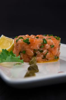 Fresh salmon tartare with lime and capers on white plate