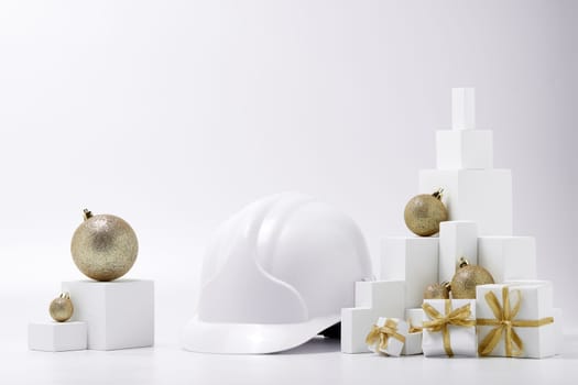 Construction hard hat, white fir tree, gift boxes and Christmas ornament on a white background with copy space. New Year and Christmas construction background