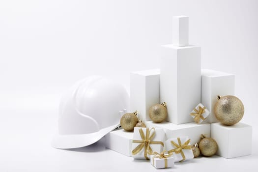 Construction hard hat, white fir tree, gift boxes and Christmas ornament on a white background with copy space. New Year and Christmas construction background