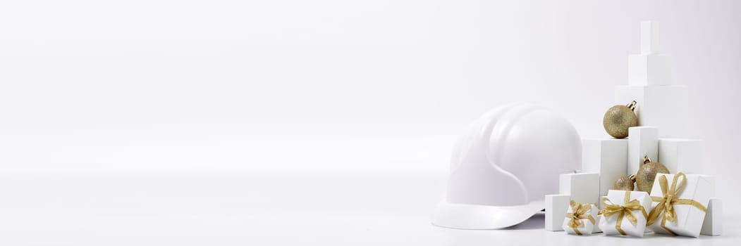 Construction hard hat, white fir tree, gift boxes and Christmas ornament on a white background with copy space. New Year and Christmas construction background