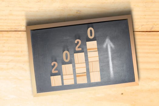 2020 on stairs of the wooden cube inside the blackboard. Happy New Year 2020