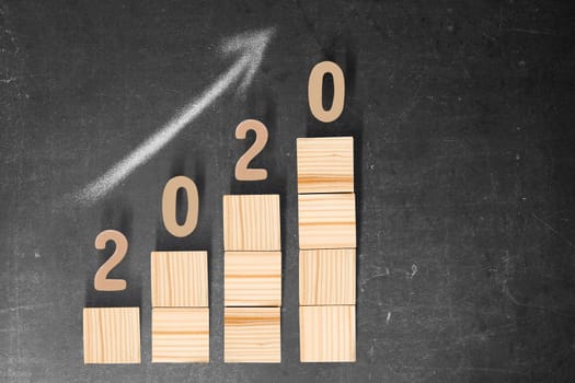 2020 on stairs of the wooden cube on the blackboard. Happy New Year 2020