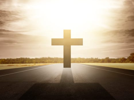 Christian cross at the end of the road with sunlight background