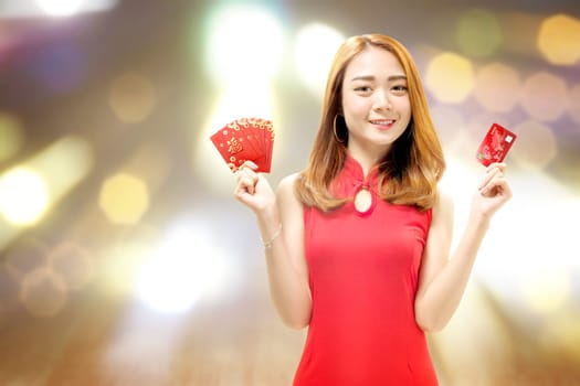 Asian Chinese woman in a cheongsam dress holding a credit card and red envelopes. Happy Chinese New Year