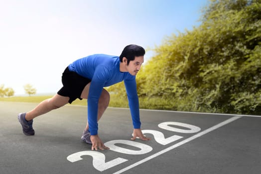 Asian runner man ready to run on the 2020 line. Happy New Year 2020