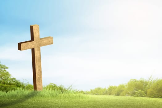 Christian cross on the green grass with sunlight and blue sky background