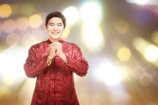 An Asian Chinese man in a cheongsam dress with congratulations gesture. Happy Chinese New Year