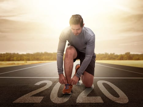 Asian runner man prepares to run on the 2020 line. Happy New Year 2020