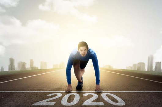 Asian runner man ready to run on the 2020 line. Happy New Year 2020