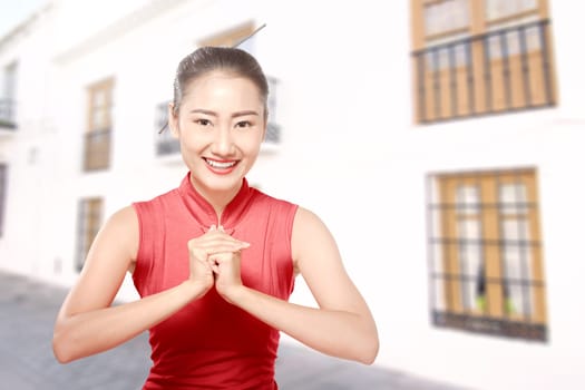 Asian Chinese woman in a cheongsam dress with congratulations gesture. Happy Chinese New Year