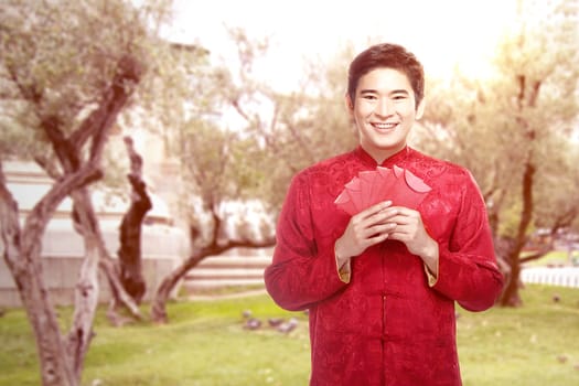 An Asian Chinese man in a cheongsam dress holding red envelopes. Happy Chinese New Year