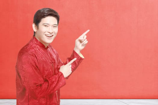 An Asian Chinese man in cheongsam dress celebrates Chinese New Year. Happy Chinese New Year