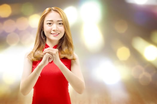 Asian Chinese woman in a cheongsam dress with congratulations gesture. Happy Chinese New Year