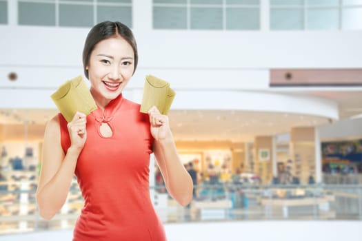 Asian Chinese woman in a cheongsam dress holding red envelopes. Happy Chinese New Year